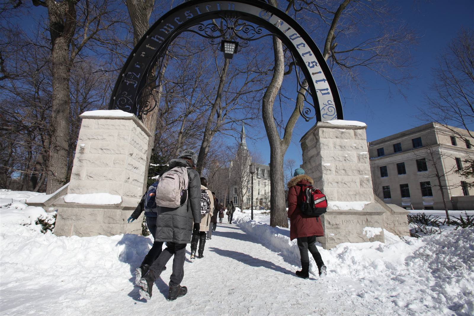Students walking through the campus arch in the snow