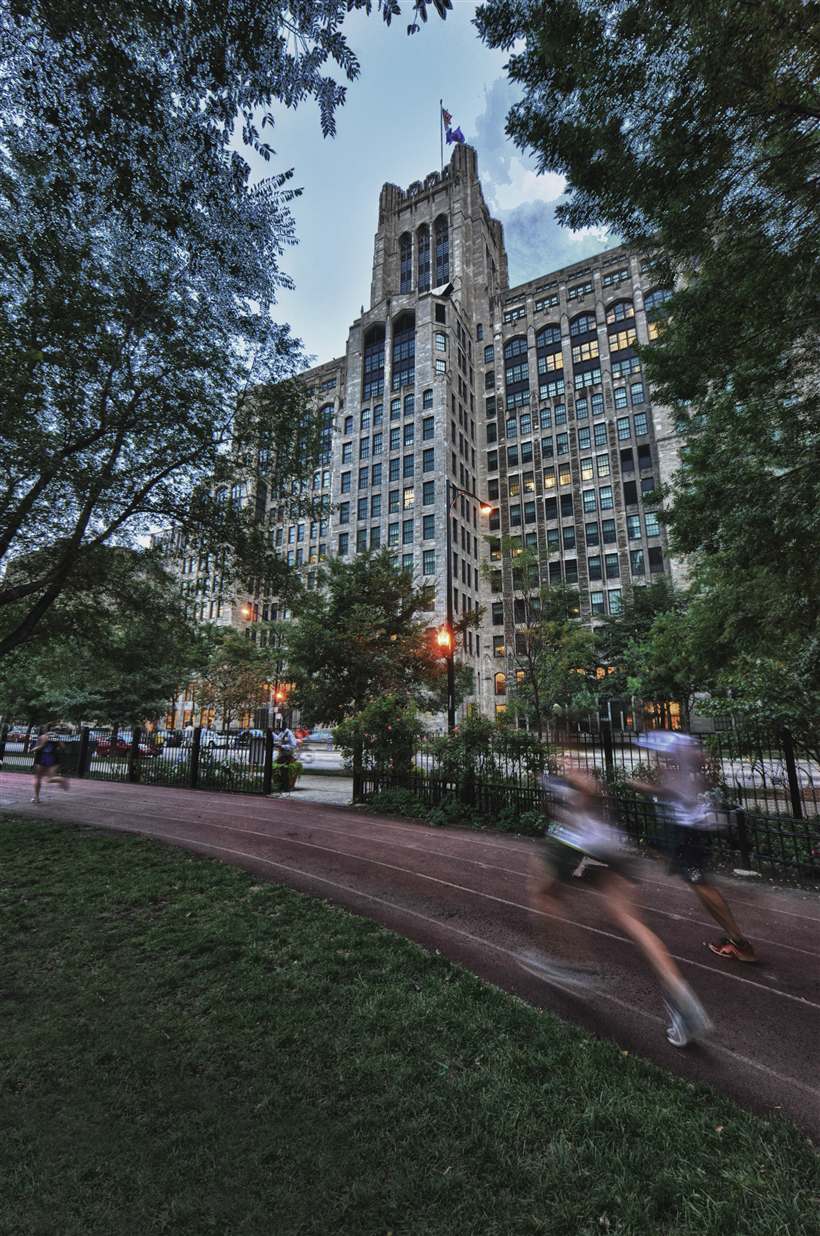 A Gothic-style tower on the Chicago campus, seen from a park path