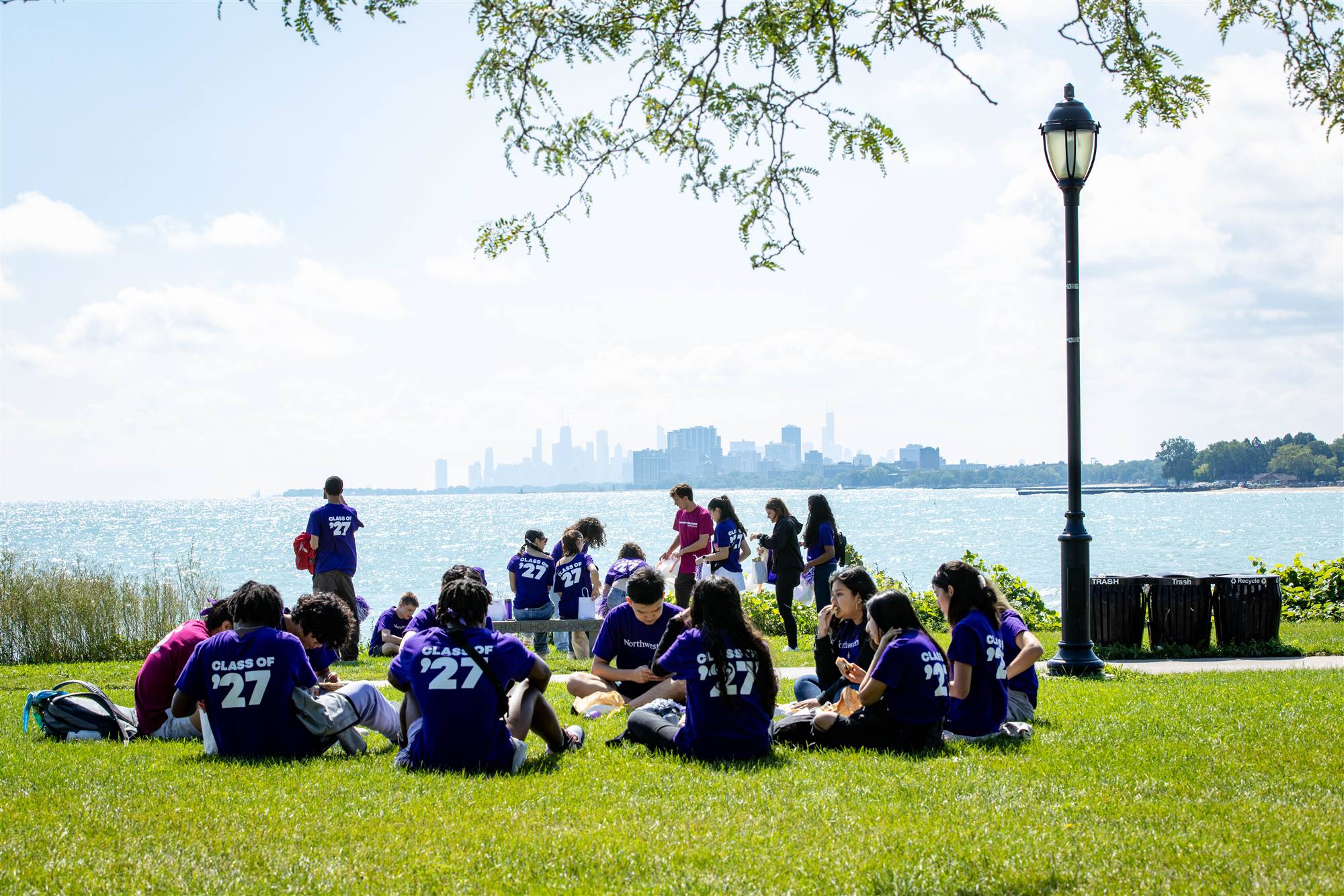 Students on the grass by the lake, the Chicago skyline in the distance