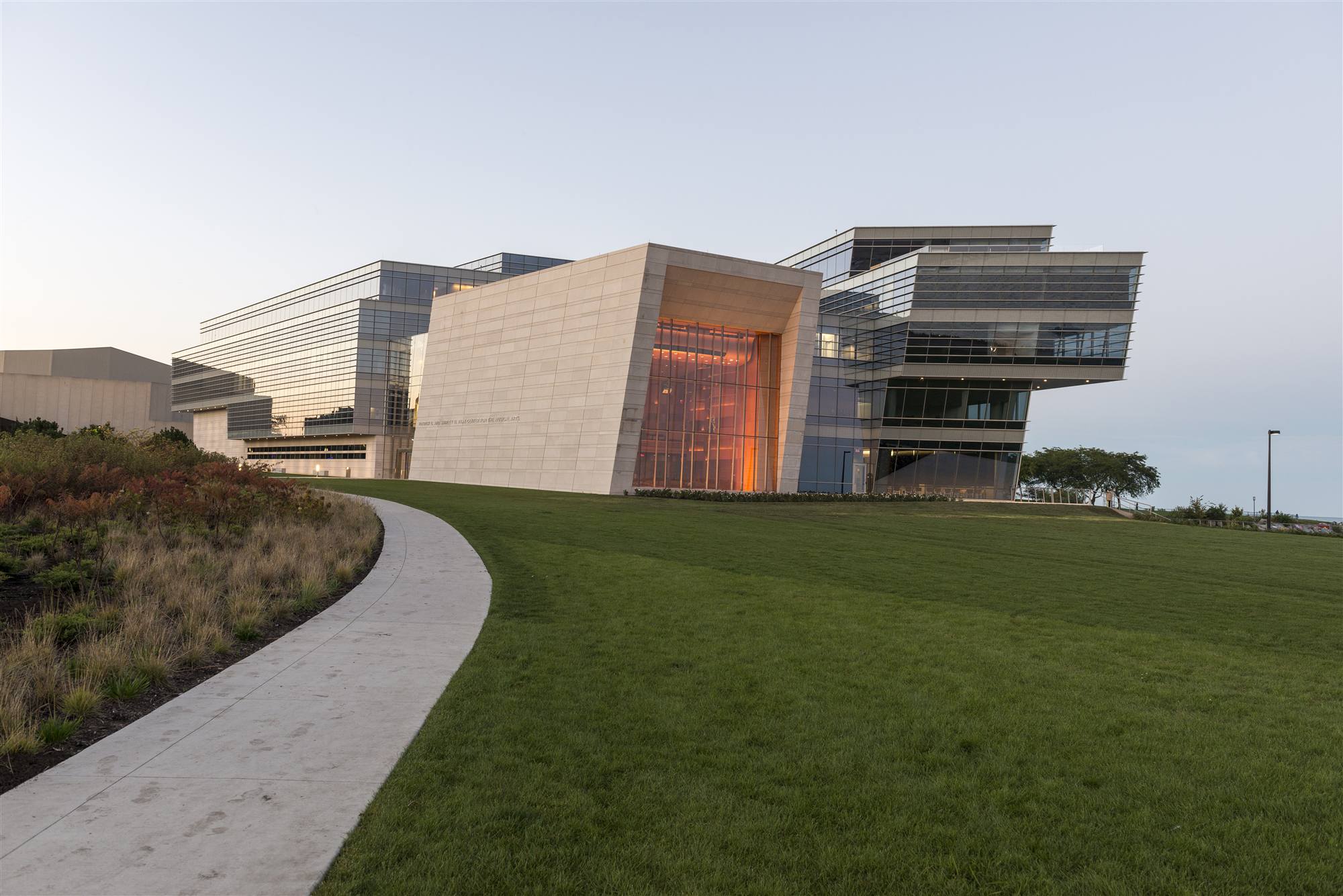 Modern athletic buildings along a lakefront path at dusk